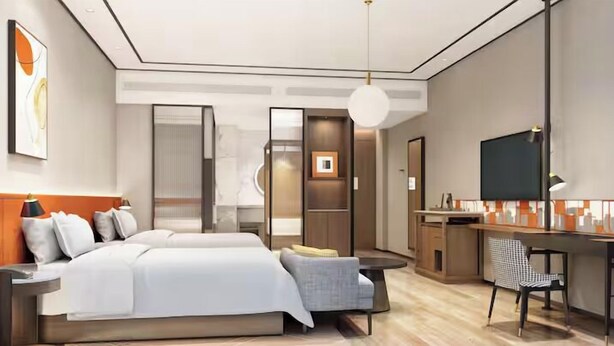 Una camera d'albergo moderna con un grande letto, una scrivania e un angolo salotto.