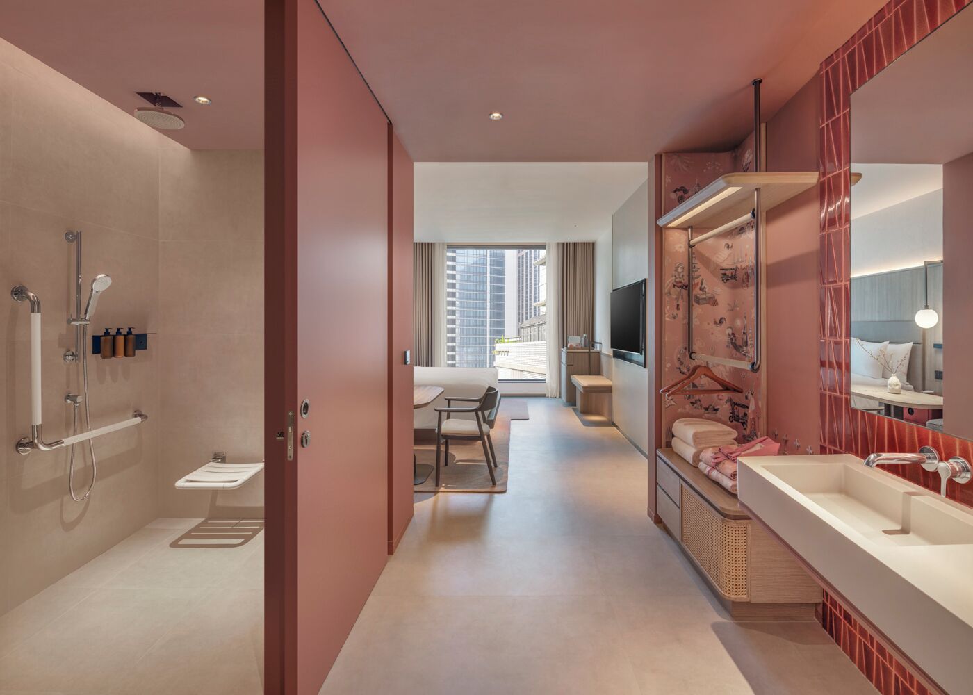 A modern bathroom with a shower, toilet, and sink. There is a dining area with a table and chairs, and a large window providing natural light.
