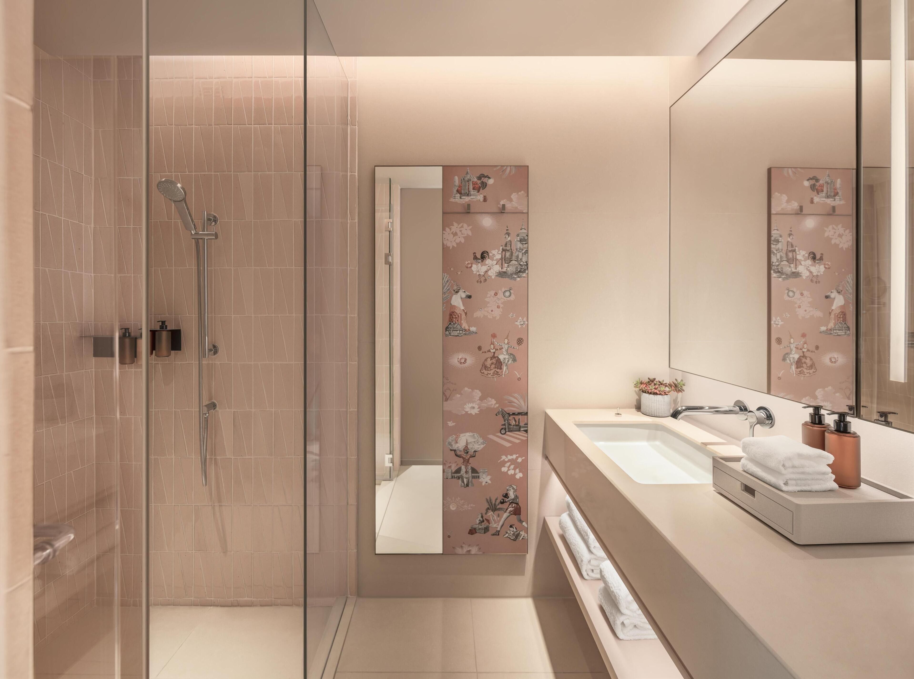Un baño moderno con ducha de vidrio, tocador con lavabo y azulejos decorativos.