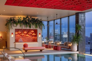 Un moderno vestíbulo de hotel con piscina, ventanas amplias y techo rojo.