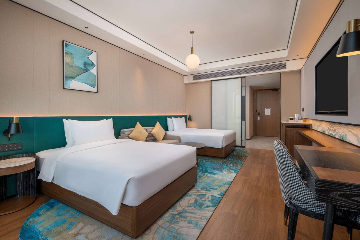 A hotel room with two beds, a desk, and a chair.