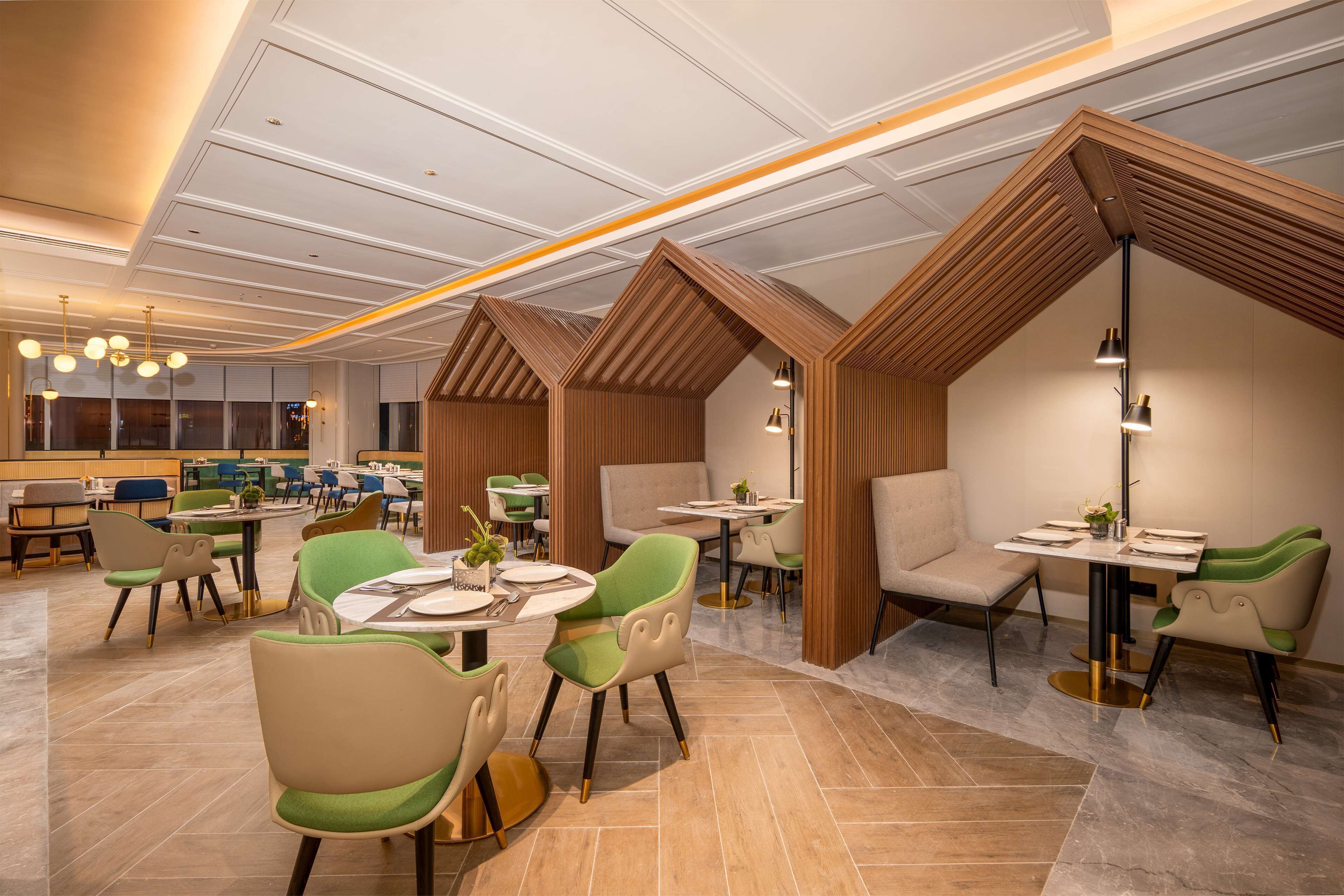 A modern dining area with round tables, green and beige chairs, and wooden accents.
