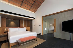 A modern hotel room with a large bed, a flat-screen TV, and a wooden ceiling.