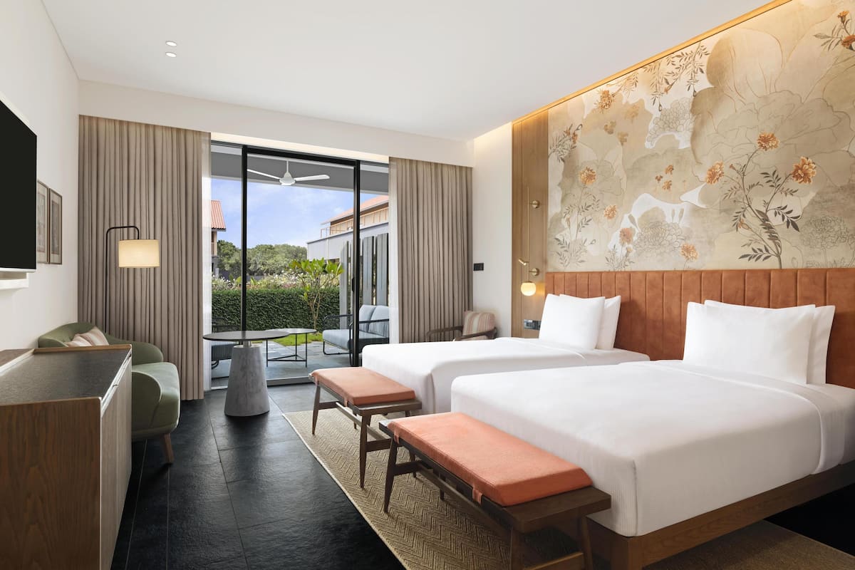 Une chambre d’hôtel avec deux lits, un bureau, une chaise et une vue sur l’extérieur.