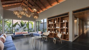 Ein modernes Interieur mit hohen Decken, einer großen Bücherwand und einer Sitzecke mit Blick auf Grünfläche.