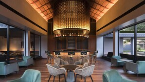 Ein modernes Interieur mit einem runden Tisch in der Mitte, umgeben von Stühlen, einer Bar und großen Fenstern mit Aussicht.