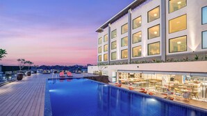 A rooftop pool area with a dining terrace, modern architecture, and a clear view of the city skyline at dusk. - Hilton Garden Inn Jabalpur (Jabalpur)