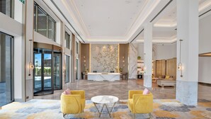 A spacious lobby with a reception desk, two yellow armchairs, and a patterned carpet. - Hilton Garden Inn Jabalpur (Jabalpur)