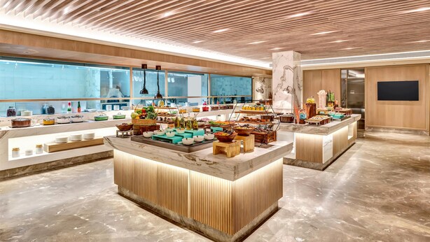 A modern hotel lobby with a central reception area featuring a marble counter, wooden accents, and a large window offering a view of the cityscape. - Hilton Garden Inn Jabalpur (Jabalpur)