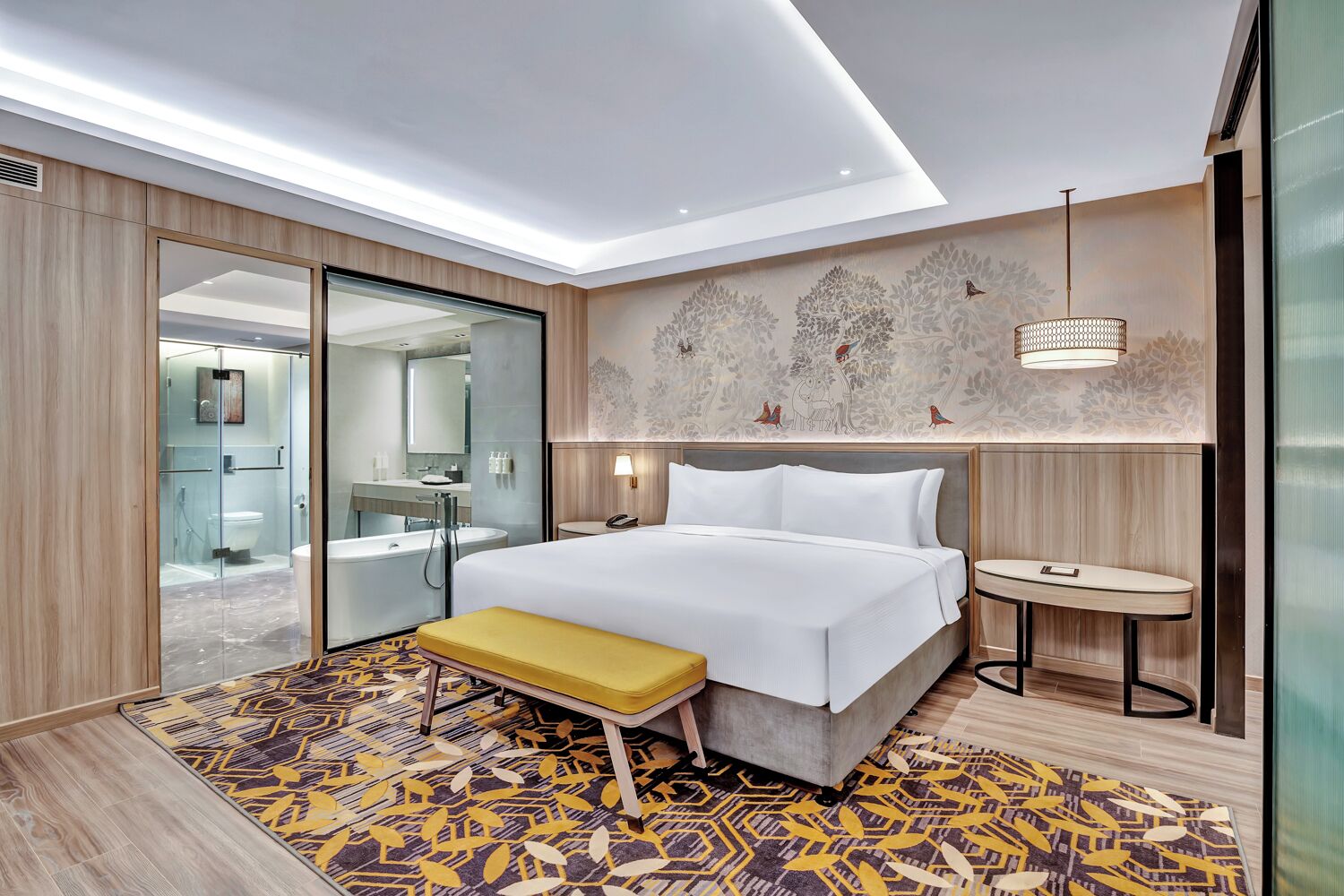 Une chambre d’hôtel moderne avec un grand lit, un banc, une petite table et un espace douche.