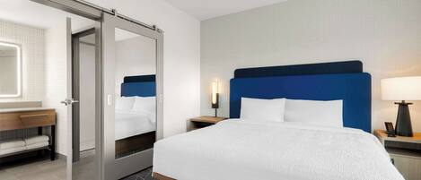 Une chambre d’hôtel avec un grand lit, une salle de bain avec un miroir et une porte coulissante.