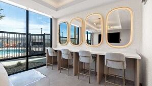 A modern bar area with a pool view, large mirrors, and bar stools. - Hampton Inn & Suites Corona, Ca (Corona)