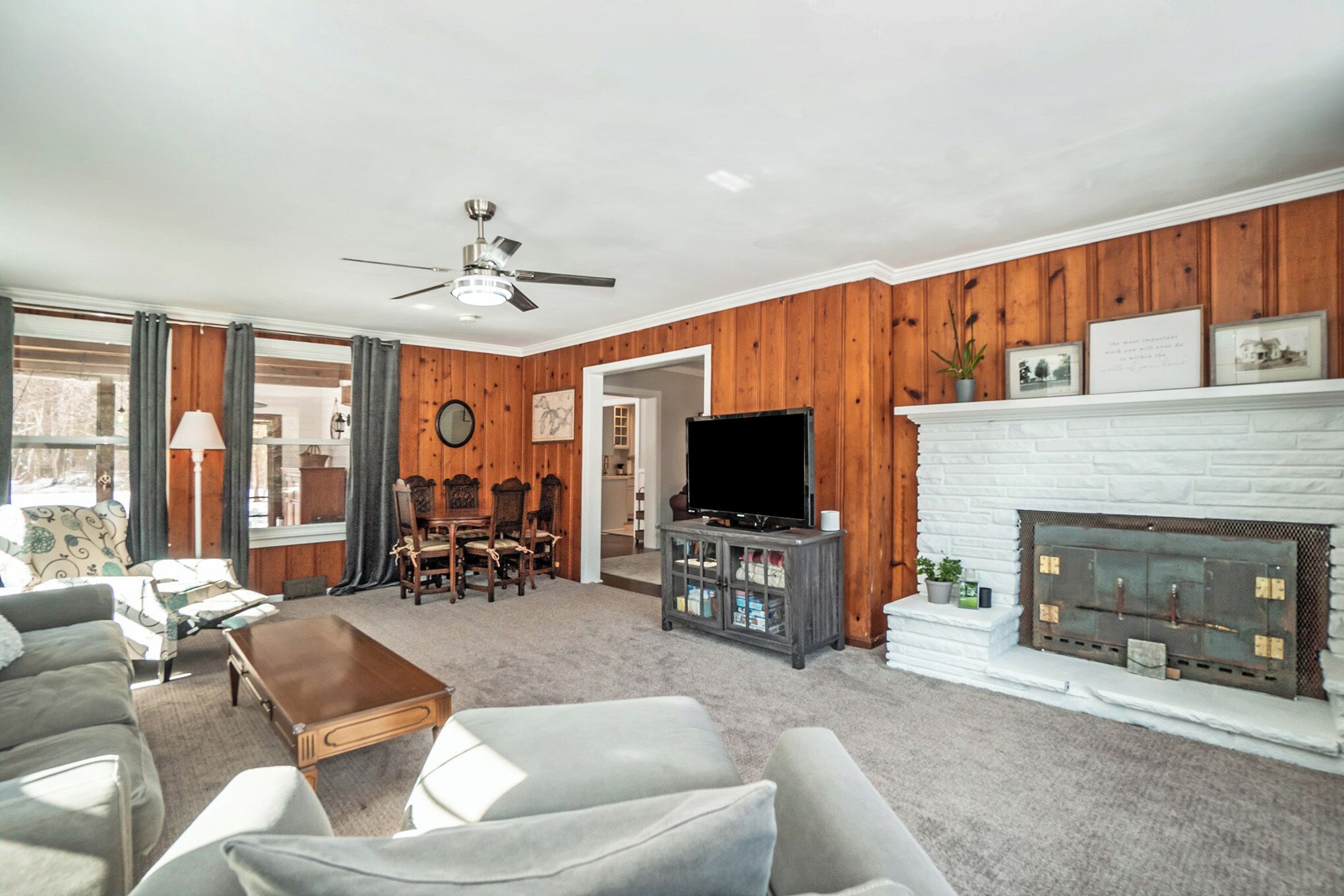 A living room with a fireplace, a television, and a ceiling fan.
