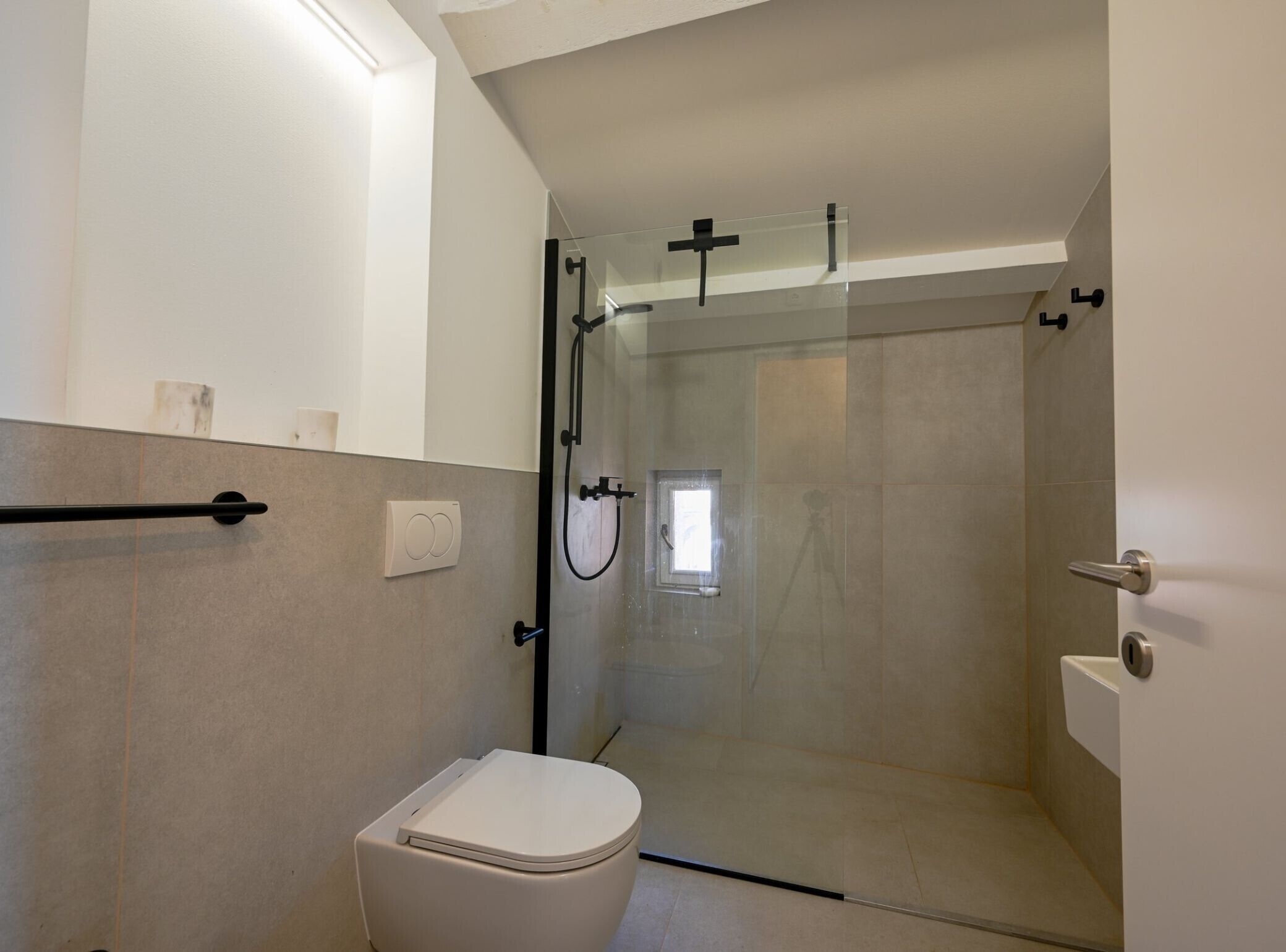 Une salle de bain moderne avec une douche à parois de verre, des toilettes blanches et un porte-serviettes.