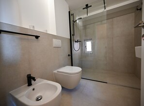 A modern bathroom with a glass-enclosed shower, a white sink, and a toilet. - Radiant and Trendy Downtown Rovinj Apartment - One Bedroom Apartment (Rovinj)