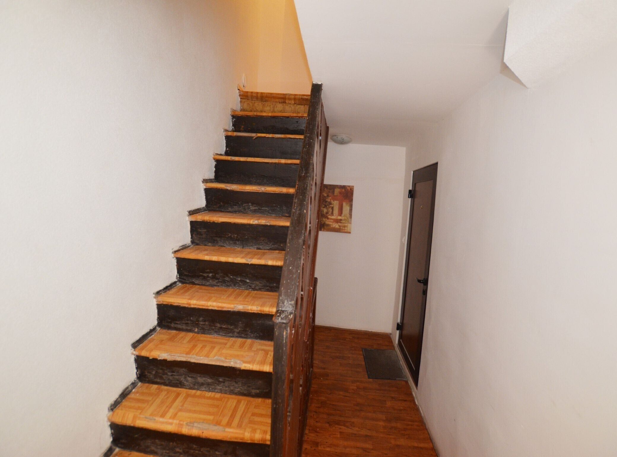 A wooden staircase with a dark finish leading to a door.
