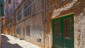 A narrow cobblestone street with historic buildings, a green door, and shuttered windows. - Sunny Rovinj Apartment with Sea View - One Bedroom Apartment with Sea View (Rovinj)