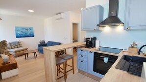 A compact kitchen with a central island, built-in oven, and light blue cabinetry. - Sunny Rovinj Apartment with Sea View - One Bedroom Apartment with Sea View (Rovinj)