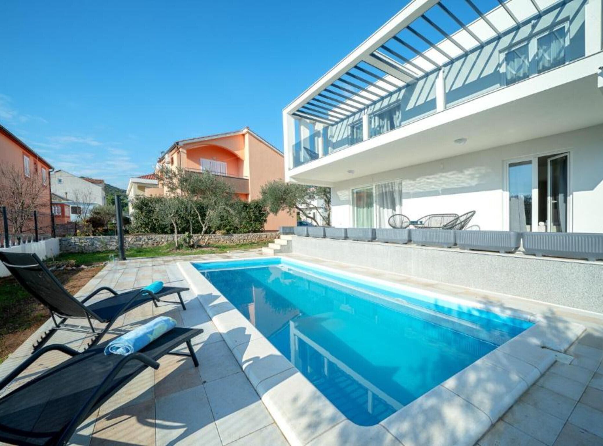 Una casa moderna con piscina, mobili da esterno e patio coperto.