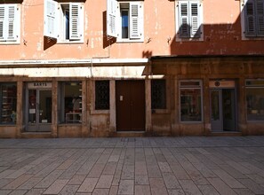 Une vue de rue avec un bâtiment dont la devanture porte l’inscription « BARTS » et un autre bâtiment dont la devanture porte l’inscription « SORINELE ».