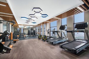 Un gimnasio moderno con cintas de correr, elípticas y equipo de levantamiento de pesas.