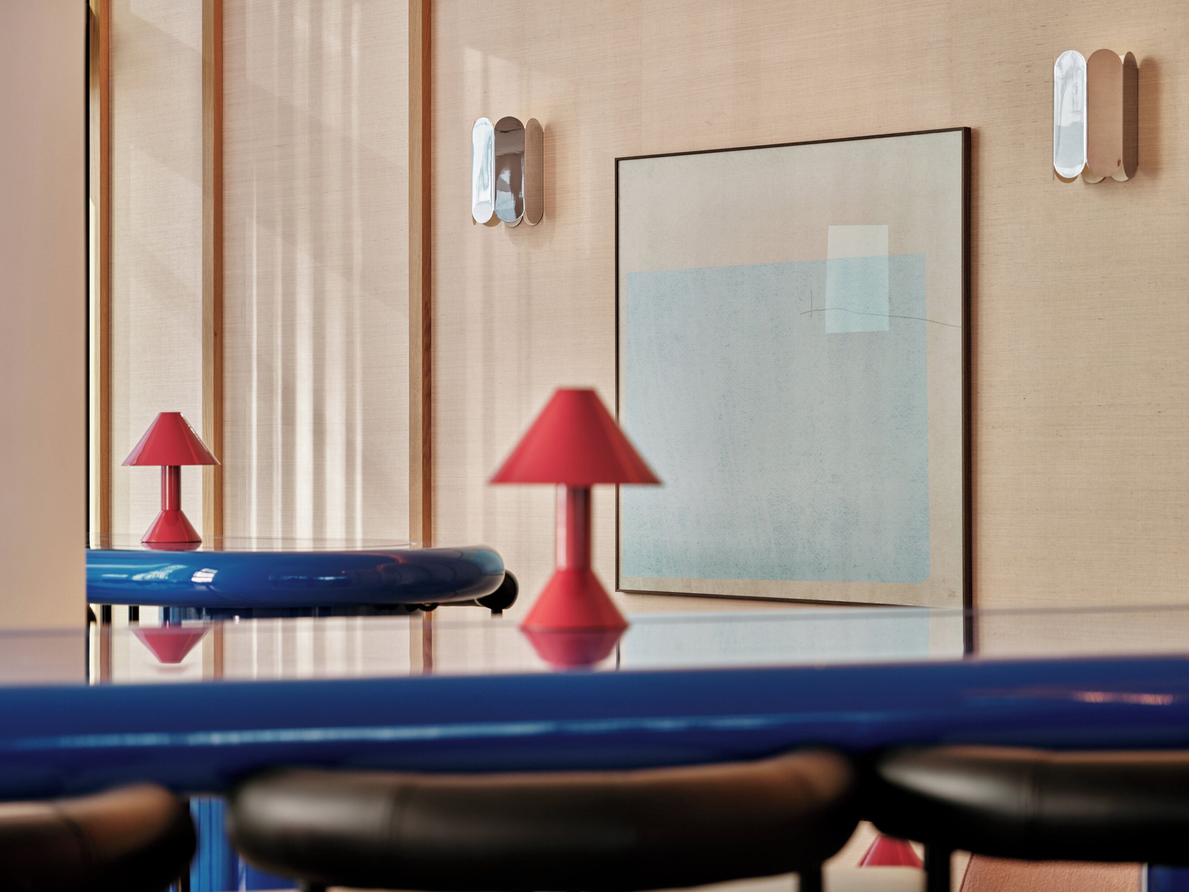 A conference room with a table, chairs, a red lamp, and a framed picture on the wall.
