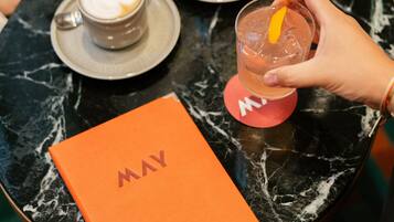 A table with a coffee cup, a glass of iced drink, and a book with the word 'MAY' on it.