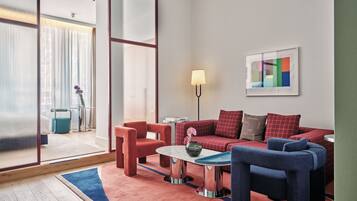 Un salon moderne avec un canapé rouge, des fauteuils bleus et une petite table basse.