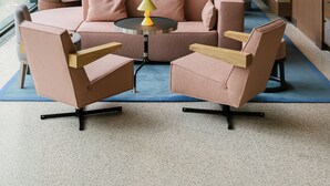 Een moderne zithoek met banken en fauteuils rond een centrale salontafel, met sfeerverlichting en een groot abstract kunstwerk aan de muur.