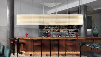 A modern bar area with a wooden counter, multiple stools, and a variety of bottles and glasses.