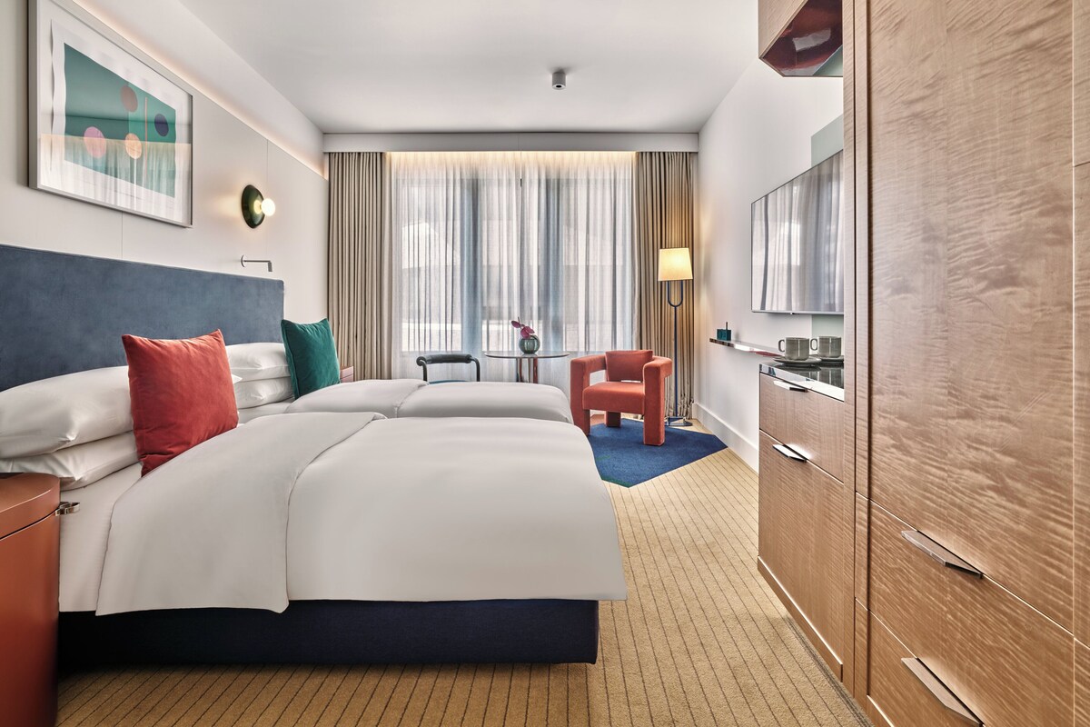 Hotelkamer met een groot bed, een bureau, een stoel, een kledingkast en een raam met gordijnen.