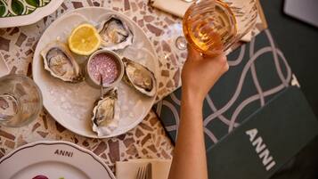 Una mesa de comedor con platos de ostras, una copa de vino y una servilleta.