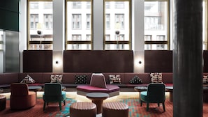 Een moderne zithoek met een bank, stoelen, poefs en een kamerkleed met een patroon.