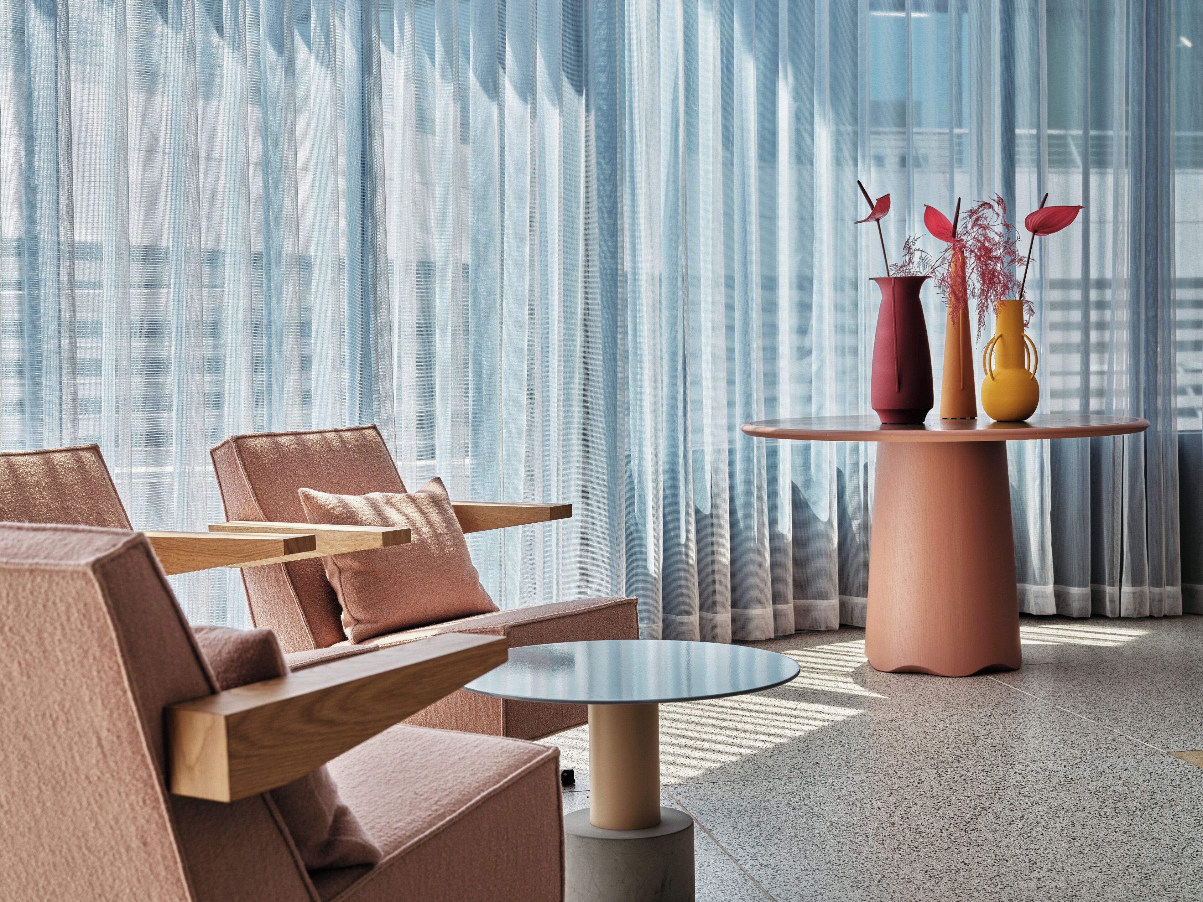 A modern interior with a round table, two chairs, and a sofa.