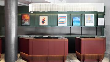 A reception area with a modern design, featuring a reception desk, a large pillar, and framed artwork on the wall.