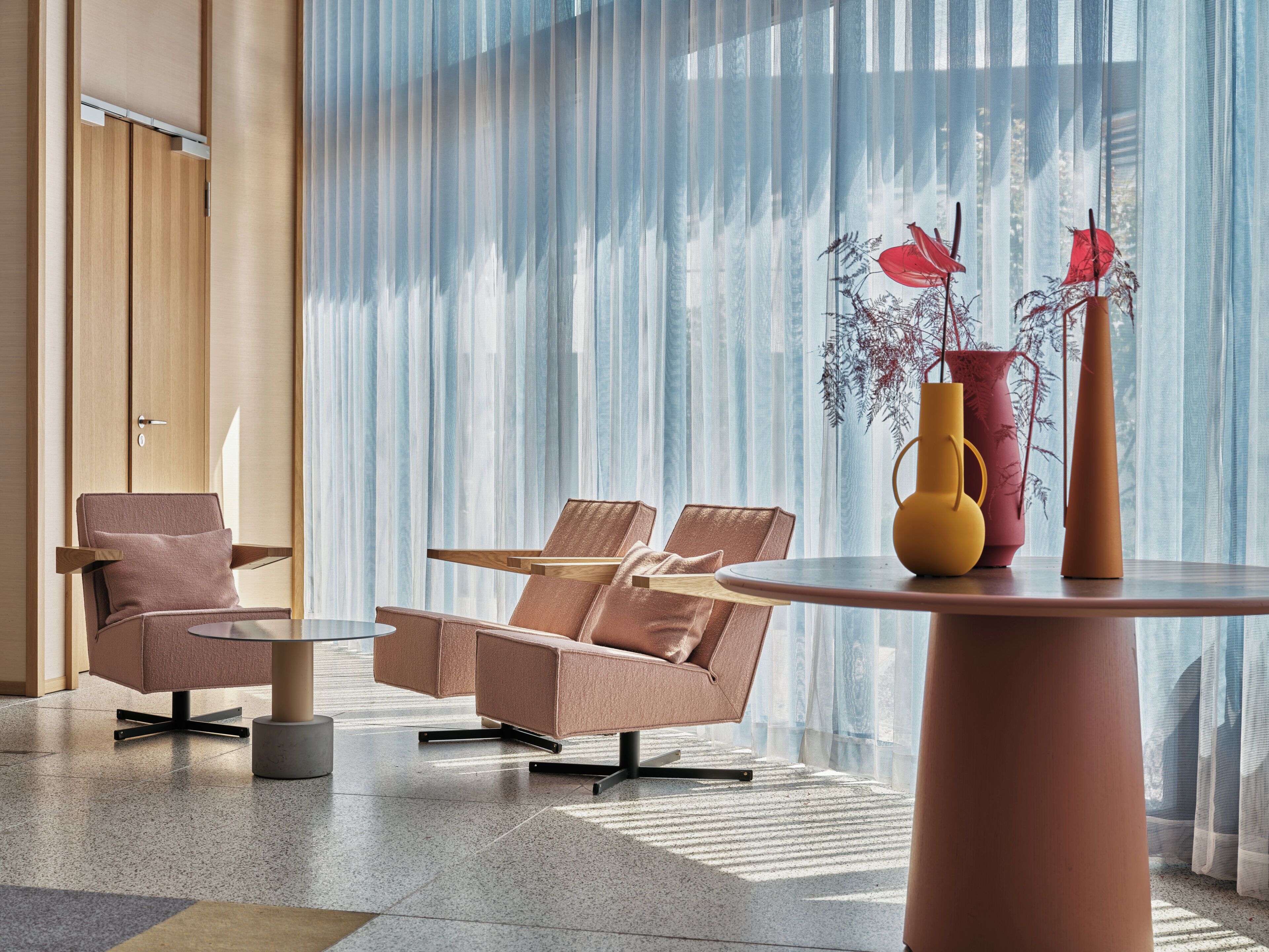 Un intérieur moderne avec deux fauteuils en cuir, une petite table ronde et un vase contenant des plantes séchées.