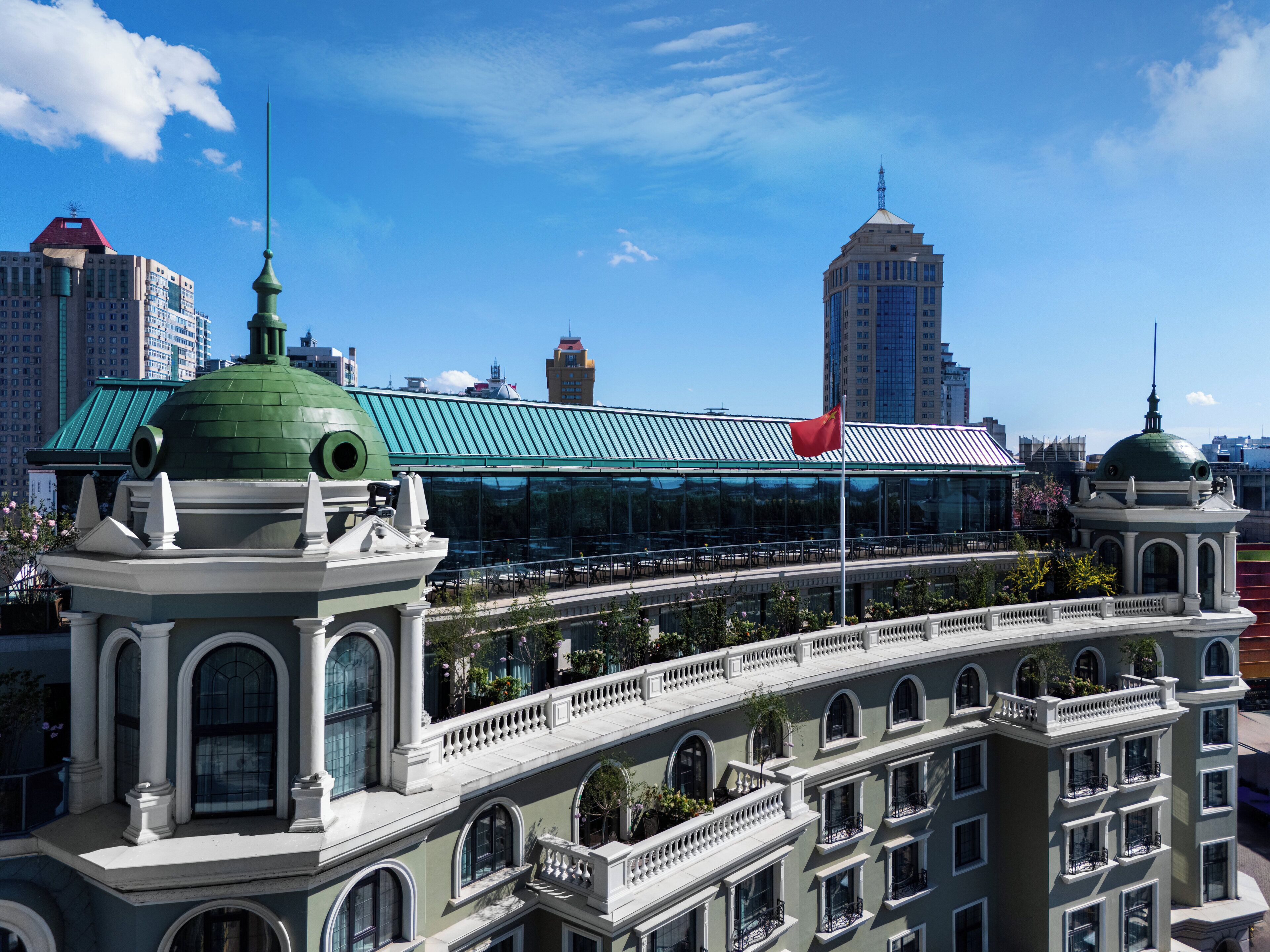 A historic building with a green dome and classical architecture, featuring multiple balconies and a central courtyard.