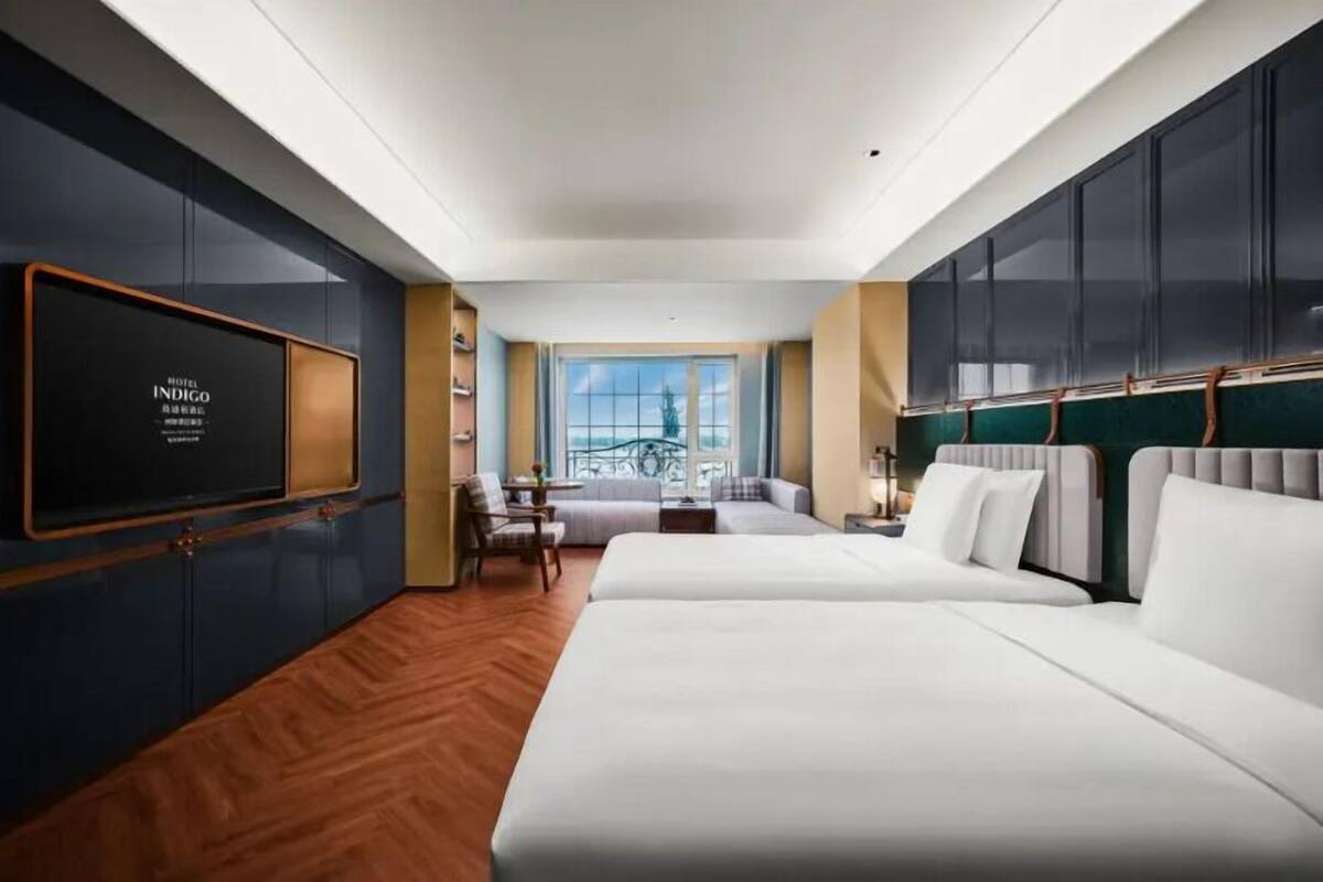 A hotel room with a large bed, a TV mounted on the wall, and a view of a bridge.