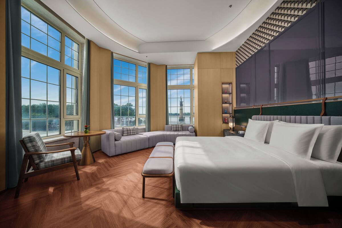 Ein geräumiges Schlafzimmer mit einem großen Bett, einer Sitzecke und Blick auf die Stadtlandschaft.
