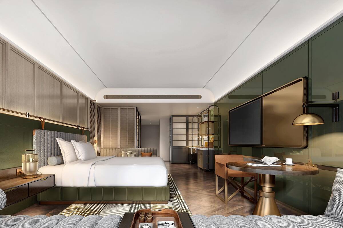 A modern hotel room with a large bed, a desk, and a seating area.
