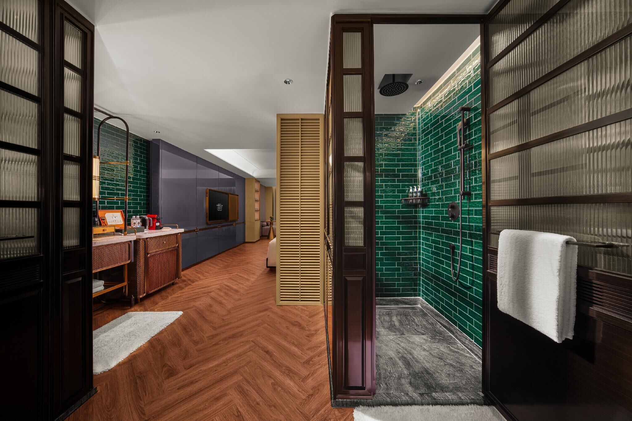 A modern bathroom with green mosaic tiles, a shower area, and a wooden floor.