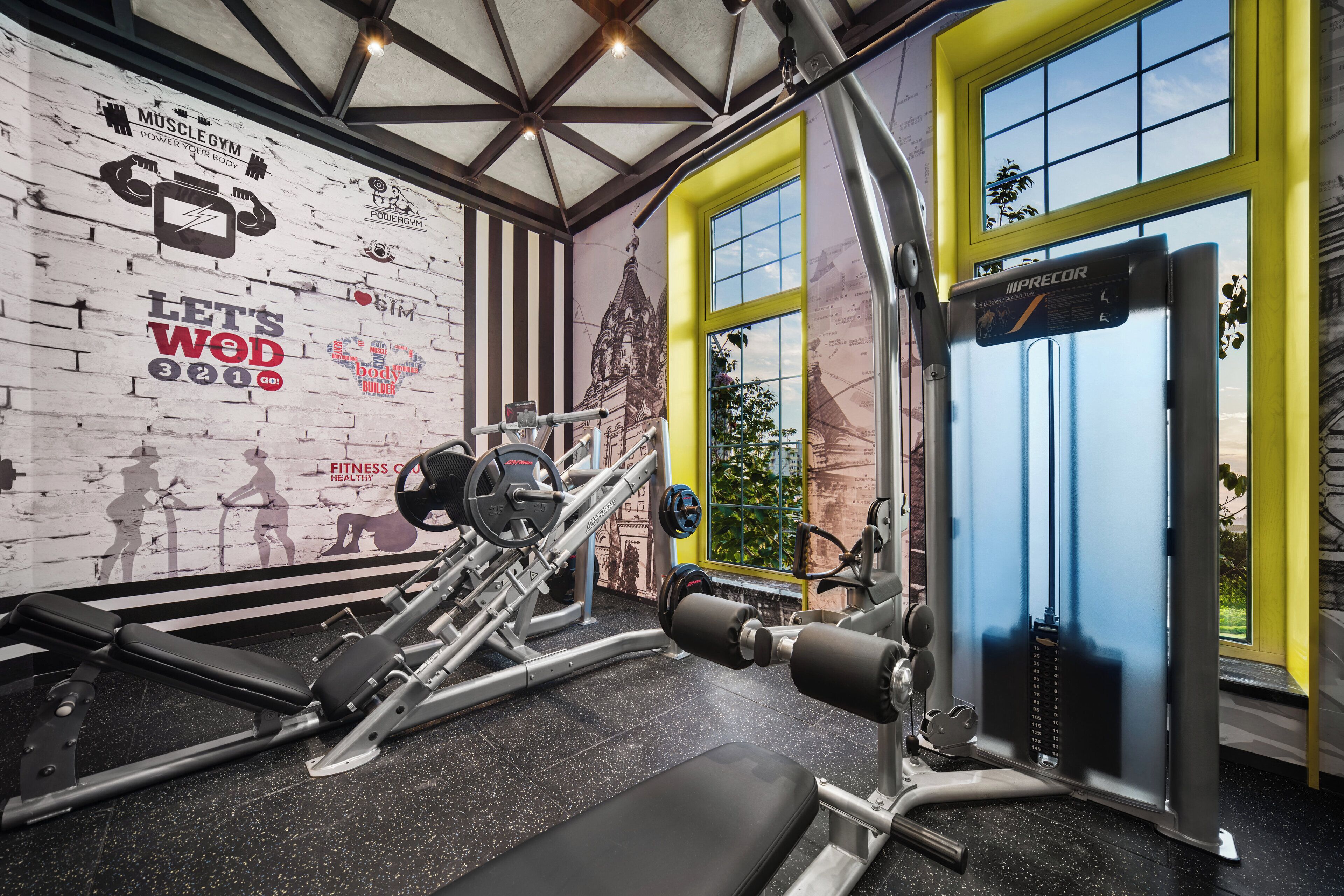 Una palestra con attrezzature per sollevamento pesi, una panca e decorazioni motivazionali alle pareti.