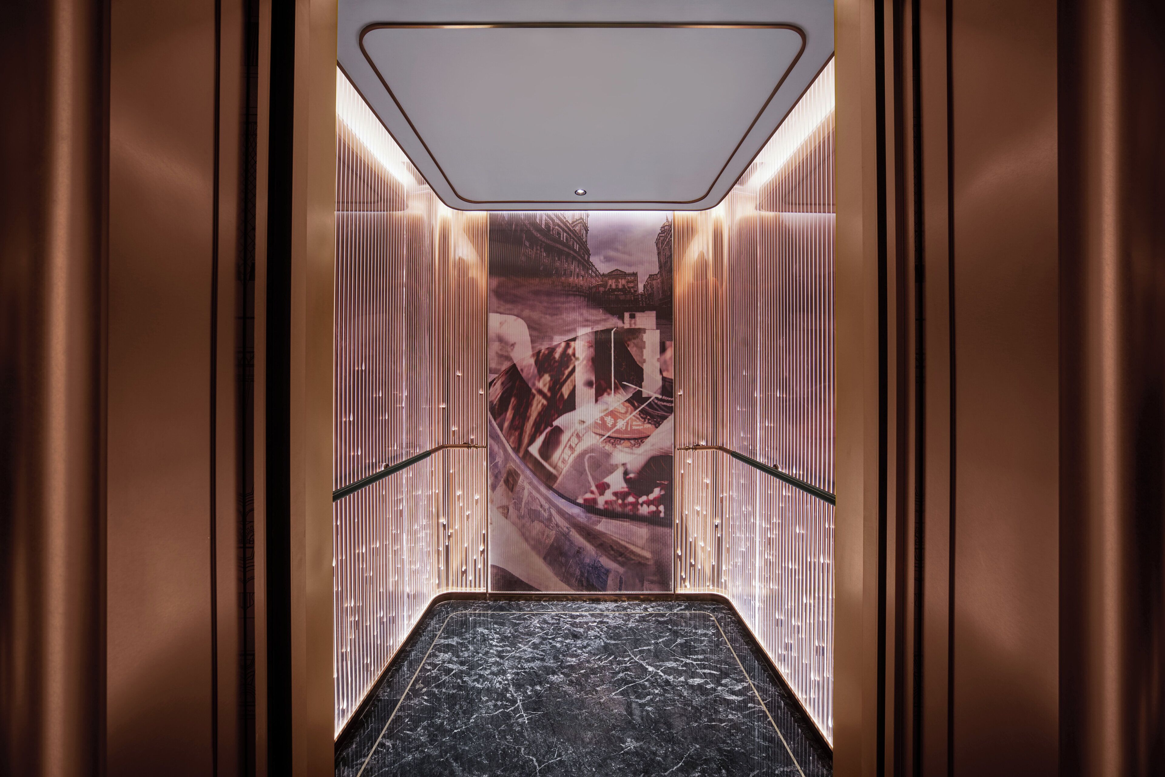 Een moderne lift met een marmeren vloer en een stadsgezichtsmural op de wanden.