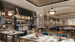 Interior de restaurante con mesas dispuestas para comer, una zona de bar y un área de estar con sillas y mesas.