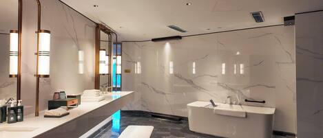 Un baño moderno con tocador de mármol, una bañera independiente y un espejo grande.