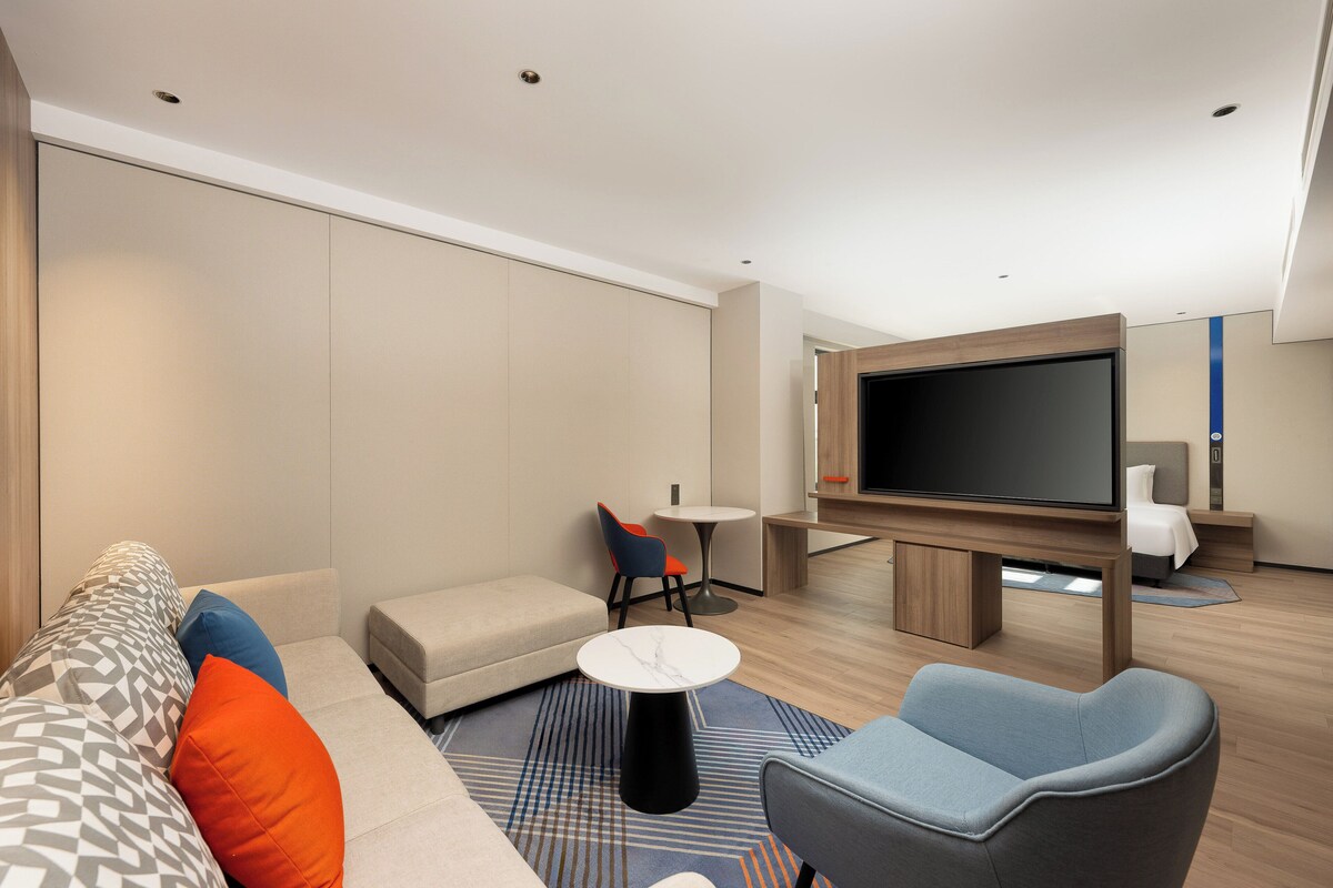 A modern living room with a sofa, armchairs, a coffee table, and a flat-screen TV.