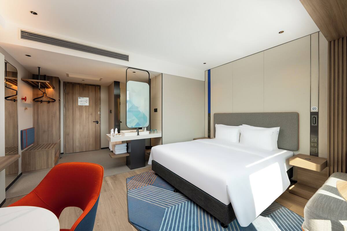 Una camera d'albergo moderna con un letto grande, una scrivania, una sedia e un bagno.