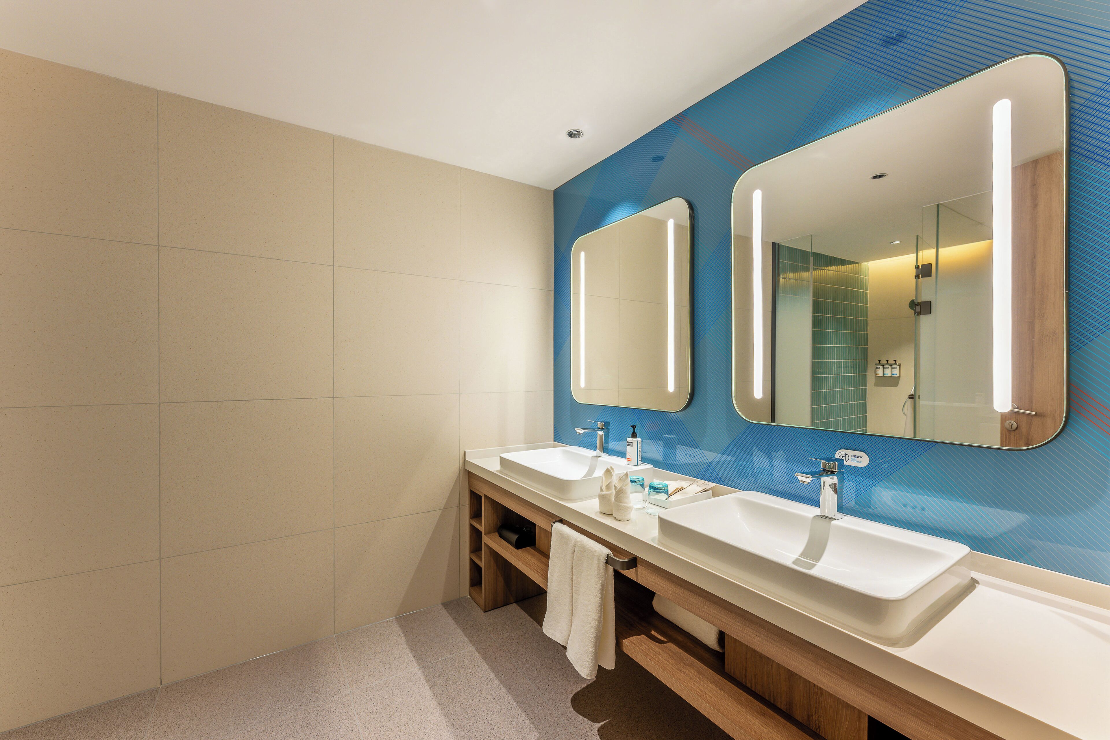 A modern bathroom with two sinks, a large mirror, and a shower area.