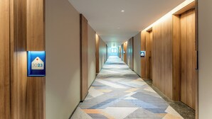 A hotel hallway with wooden walls, a patterned carpet, and numbered doors. - Holiday Inn Express Luoyang Longmen by IHG (Luoyang)