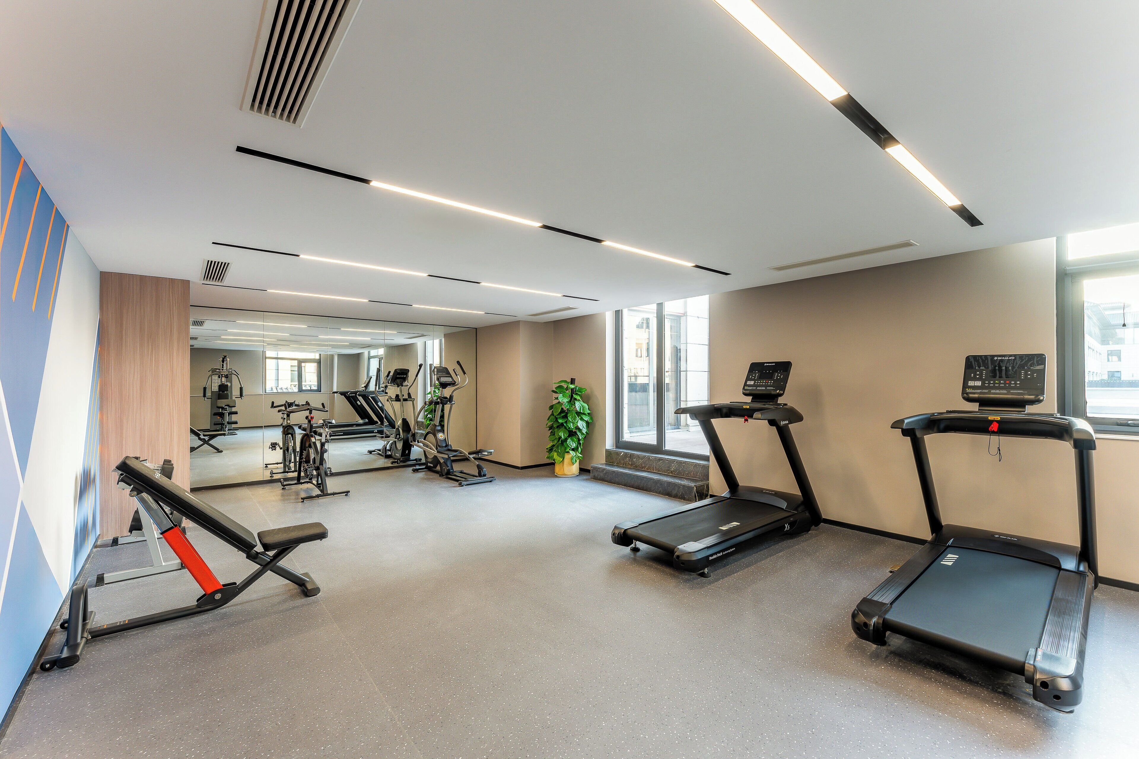 Une salle de sport équipée de tapis de course, d’appareils de musculation et d’autres équipements d’exercice.